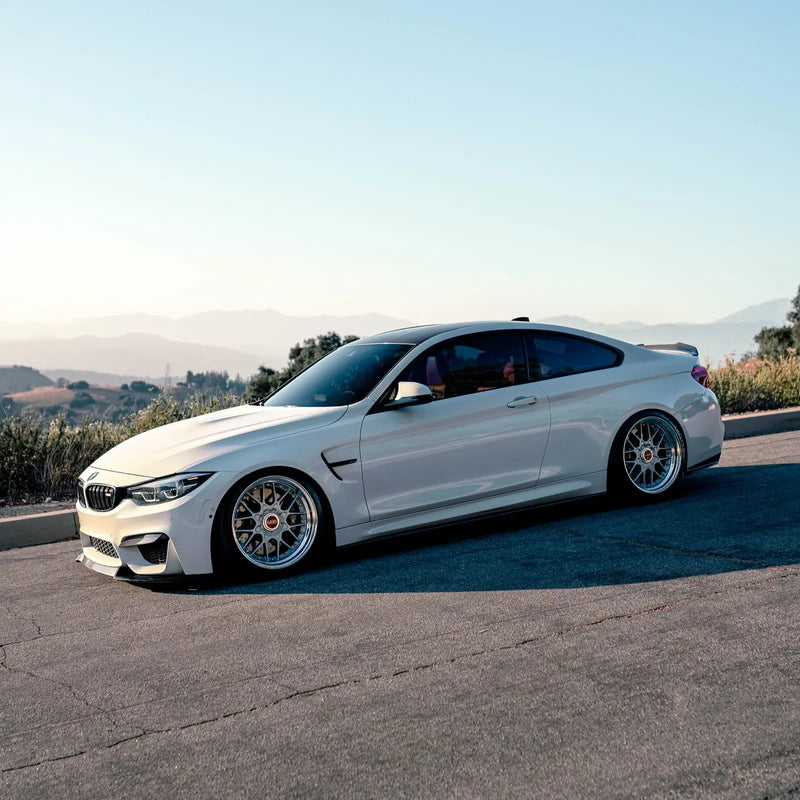 White BMW F82 M4 on a road with a scenic background